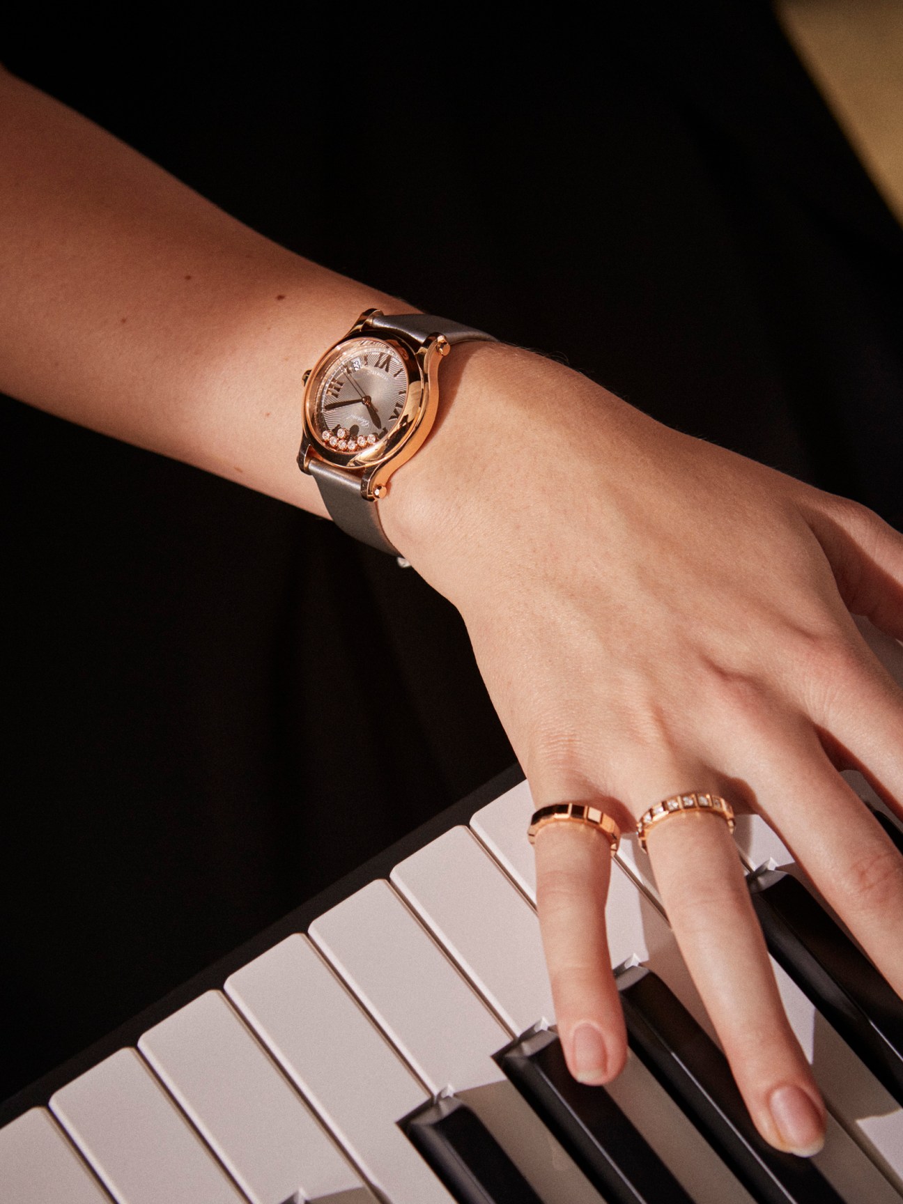 Happy Sport by Chopard watch with diamond bezel on woman's wrist with gold rings.