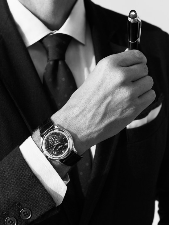 Man in business suit holding Montblanc pen, wearing Patek Philippe watch and Drake's tie.
