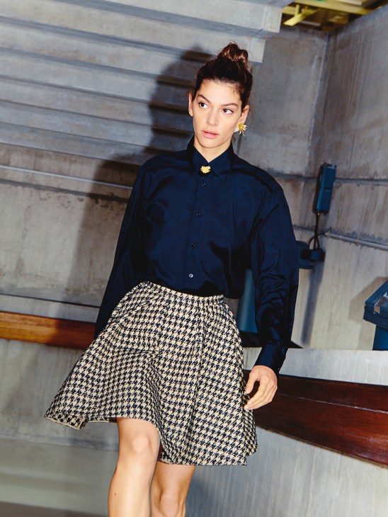 Model wearing navy shirt, houndstooth skirt, and gold jewelry by Dior.