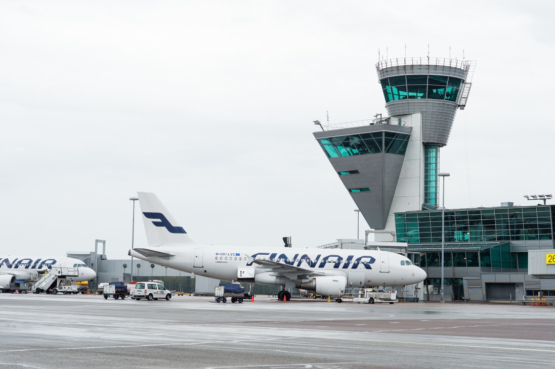 Finnair Airbus A319 parked at Helsinki Airport with control tower in background.