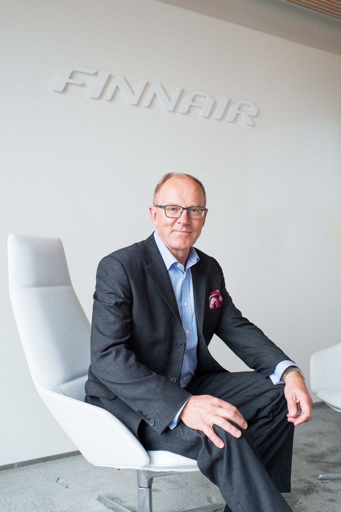 Finnair CEO Pekka Vauramo sits in a white chair at the airline's headquarters.
