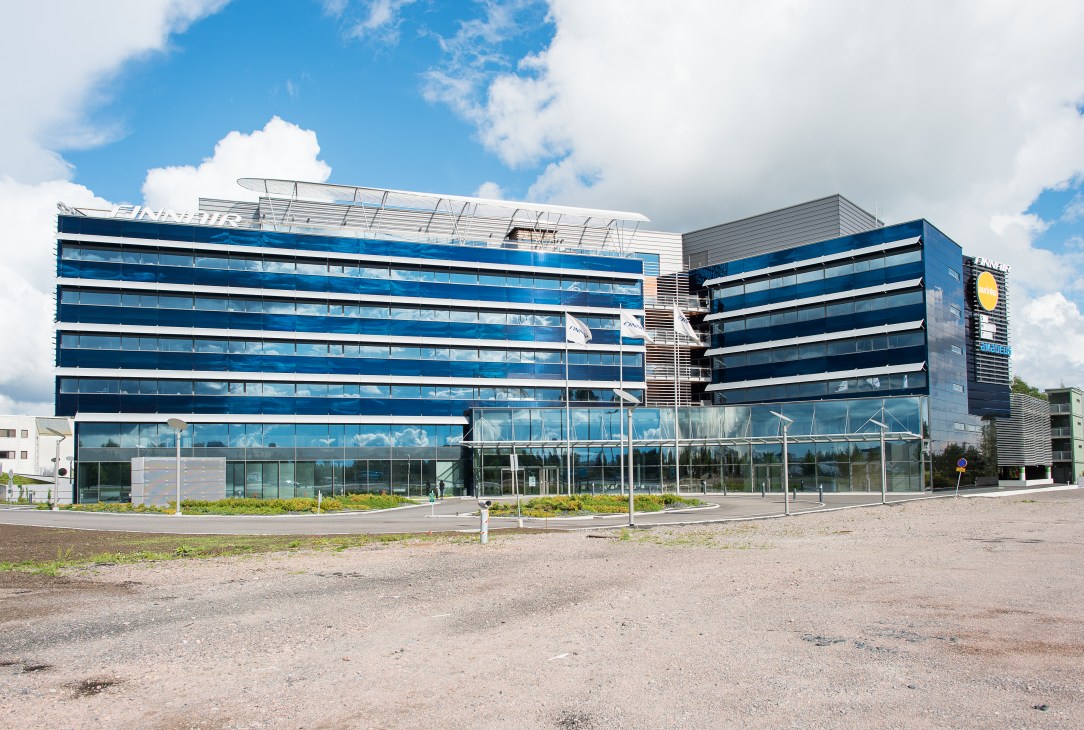 Modern multi-story office building with blue and white striped facade at Finnair's Helsinki headquarters.