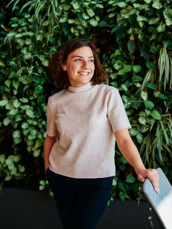 Suzanna Shamakhyan, Fast's vice-president of partnerships and programmes, smiles in front of a green foliage wall.