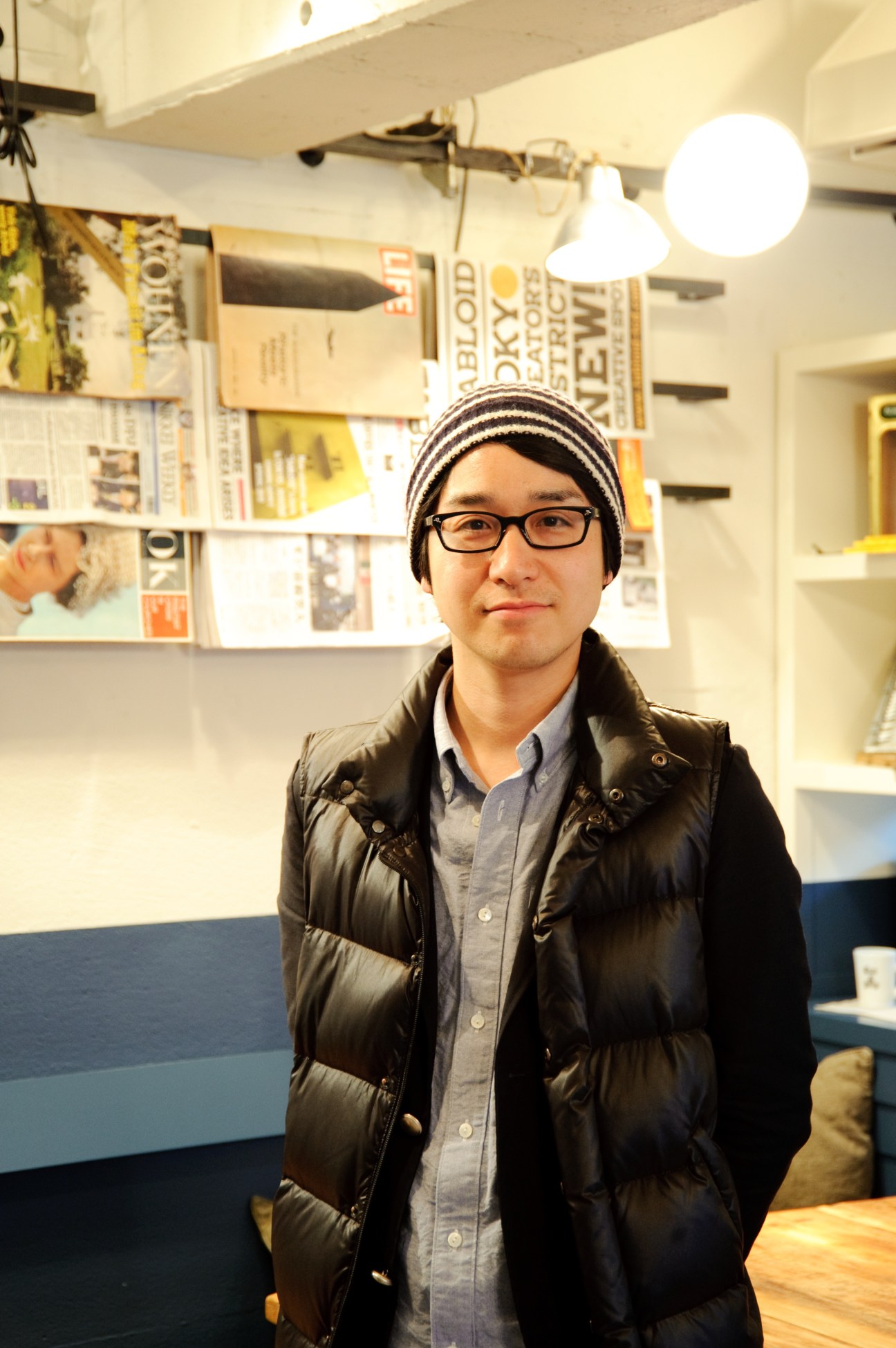 Yusuke Kawamata, general manager of Think Green Produce, standing in an office with shelves of magazines behind him.