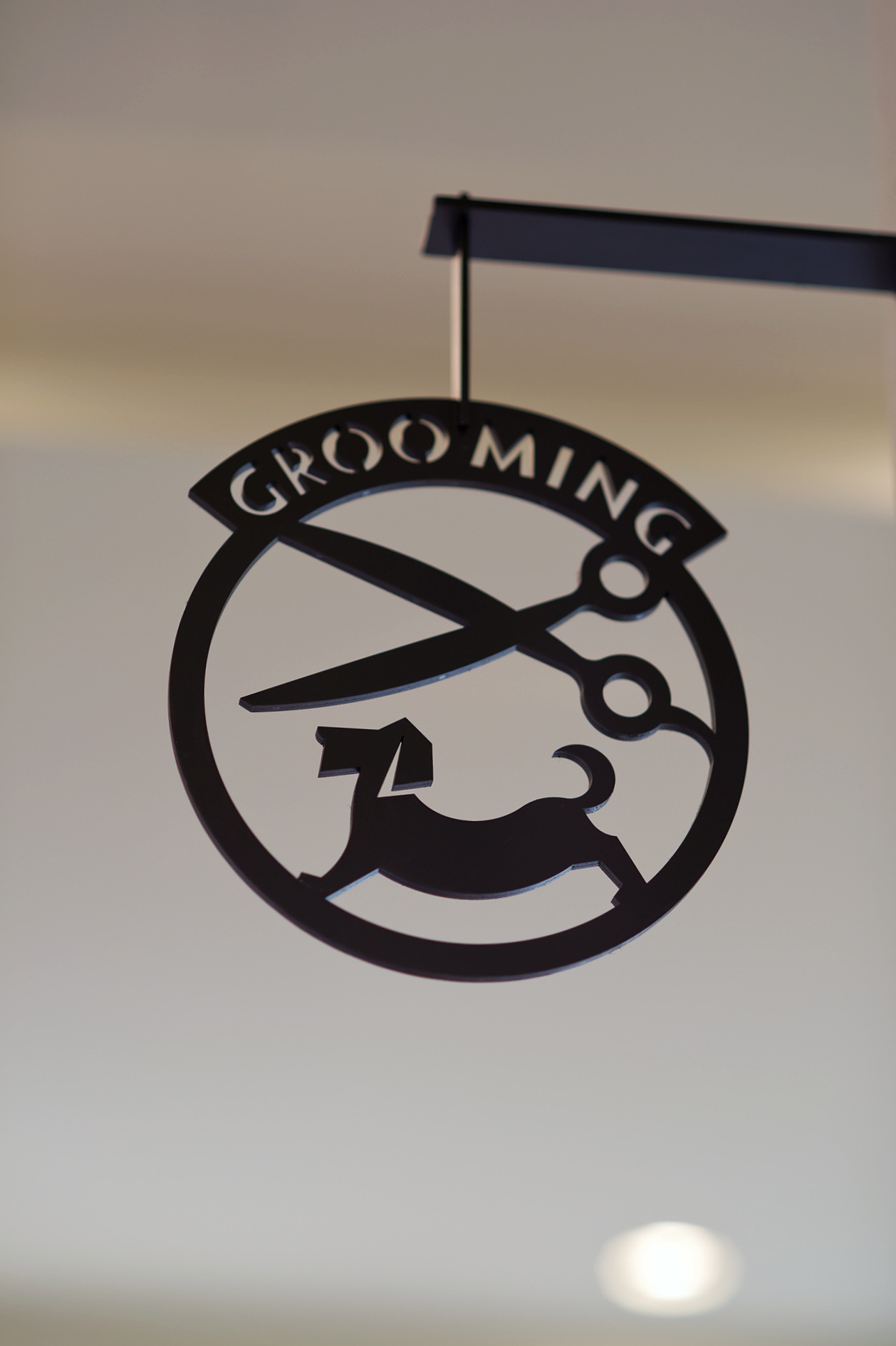 Black silhouette sign showing a dog grooming logo with scissors and a dog profile.