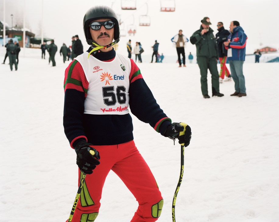 Moroccan military skier in competition gear on snowy slope with spectators in background.