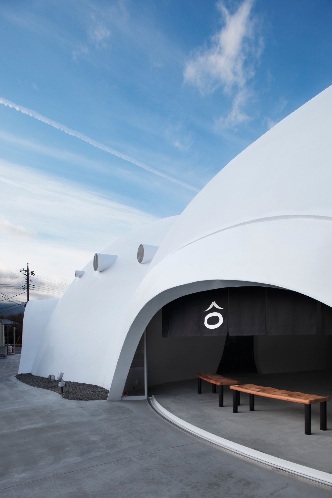 White igloo-like Hoto Fudo restaurant building with circular entrance and ventilation ports under blue sky.