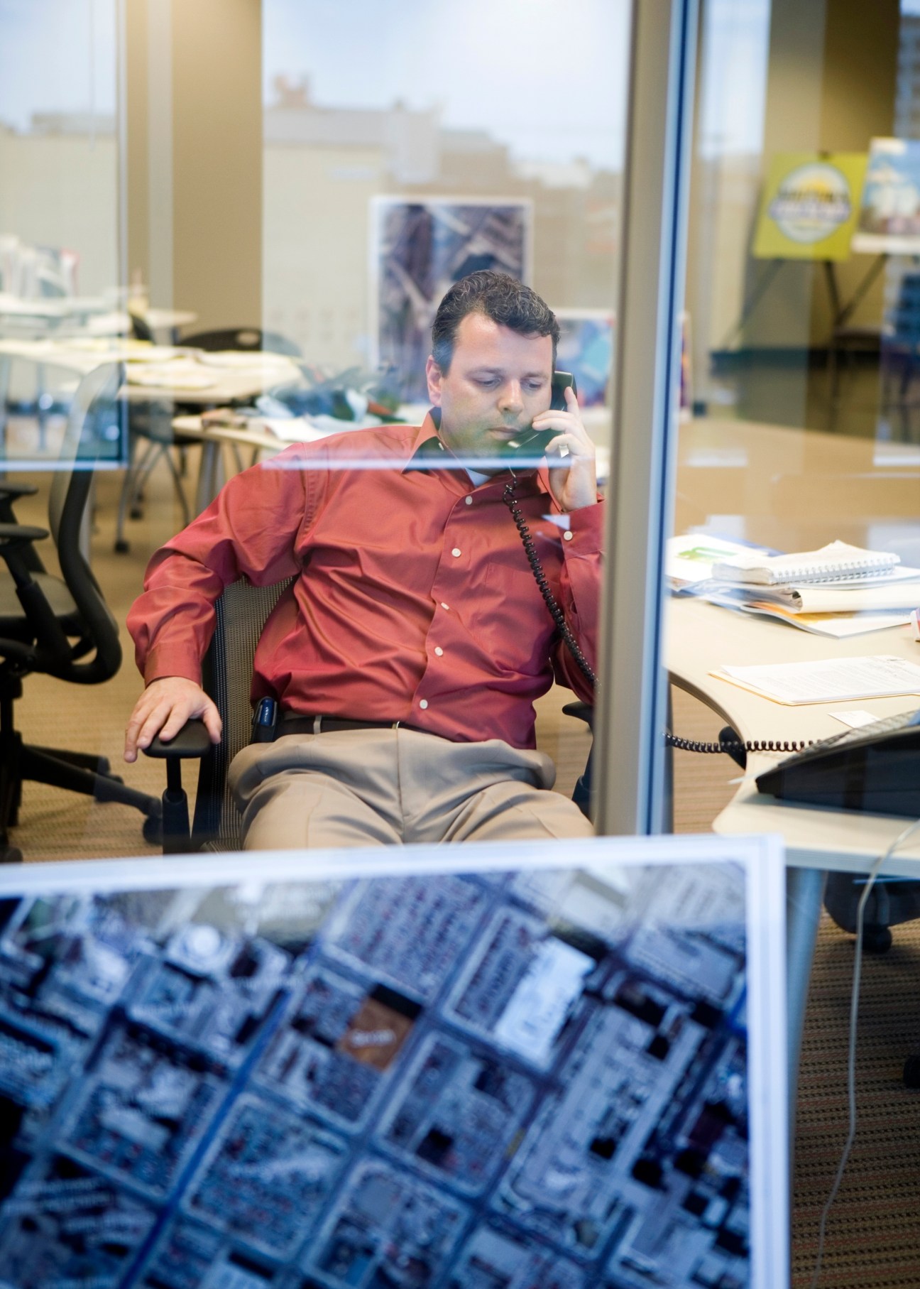 Kim Havey, a Kandiyohi partner, sits at an office desk speaking on a phone wearing a red shirt.