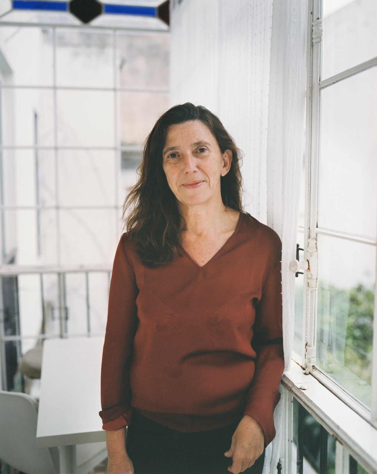 Mirentxu Ormatxea, an architect, stands by a large window wearing a rust-colored sweater.