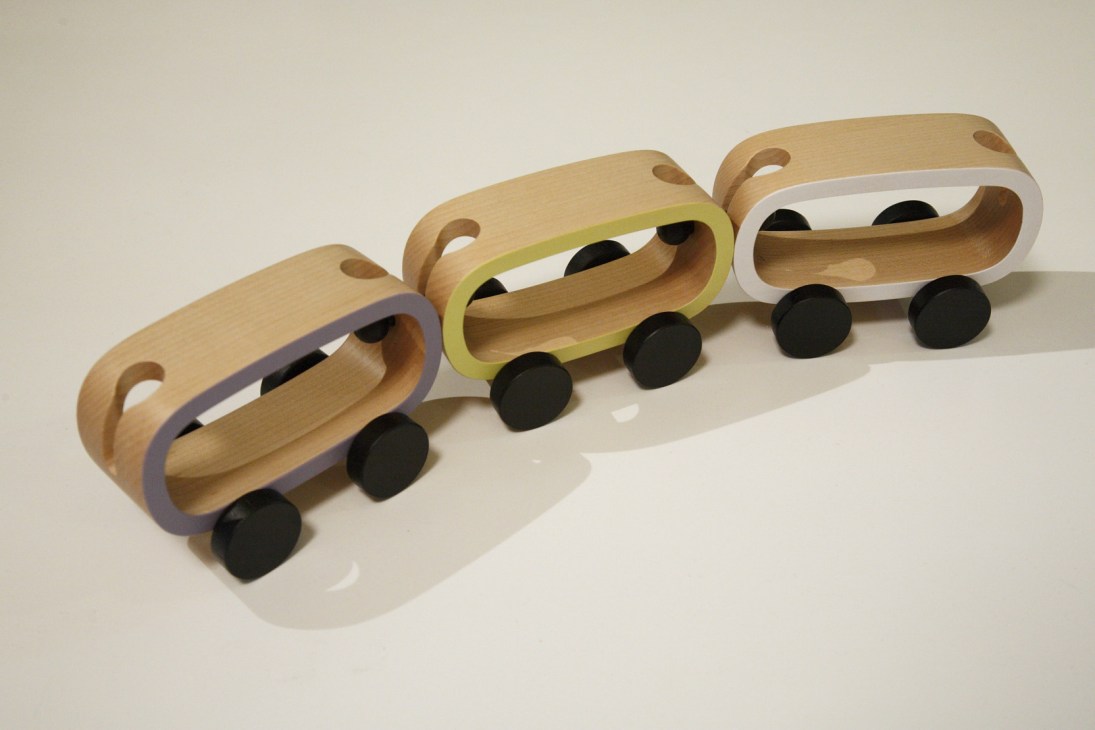 Three wooden toy trains with colored bands and black wheels displayed in a row.