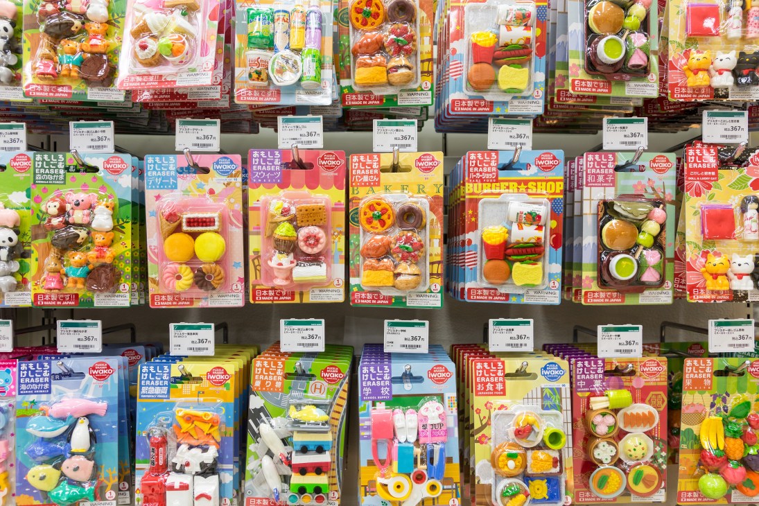 Display wall of colorful novelty erasers and toy sets packaged in plastic cases at Tokyu Hands.