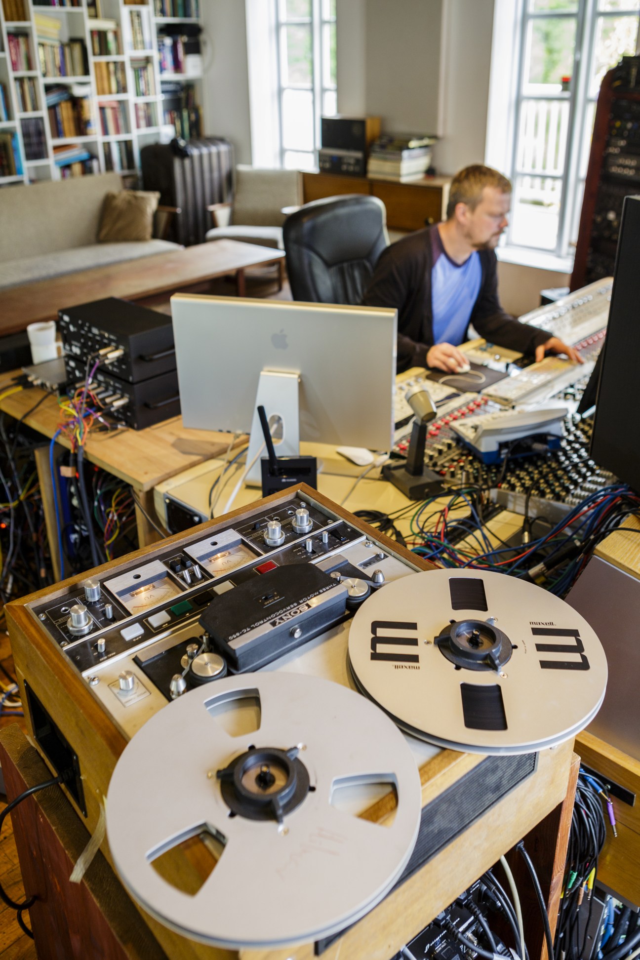 Birgir Jón 'Biggi' Birgisson works at a mixing console in Sundlaugin recording studio with reel-to-reel tape machines in the foreground.
