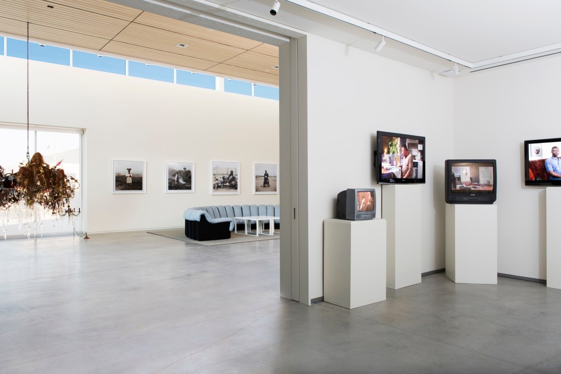 Gallery space at 21c Hotel displaying artwork on white walls and pedestals with video screens.