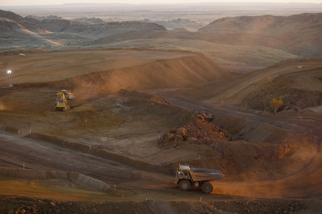 Mining trucks and excavation equipment at an iron ore mine site in Western Australia's Pilbara region.