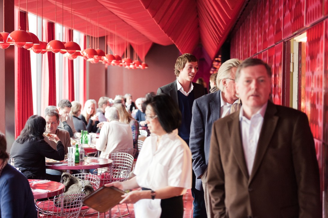 Der Spiegel staff mingling in a vibrant red-lit canteen with hanging pendant lights.