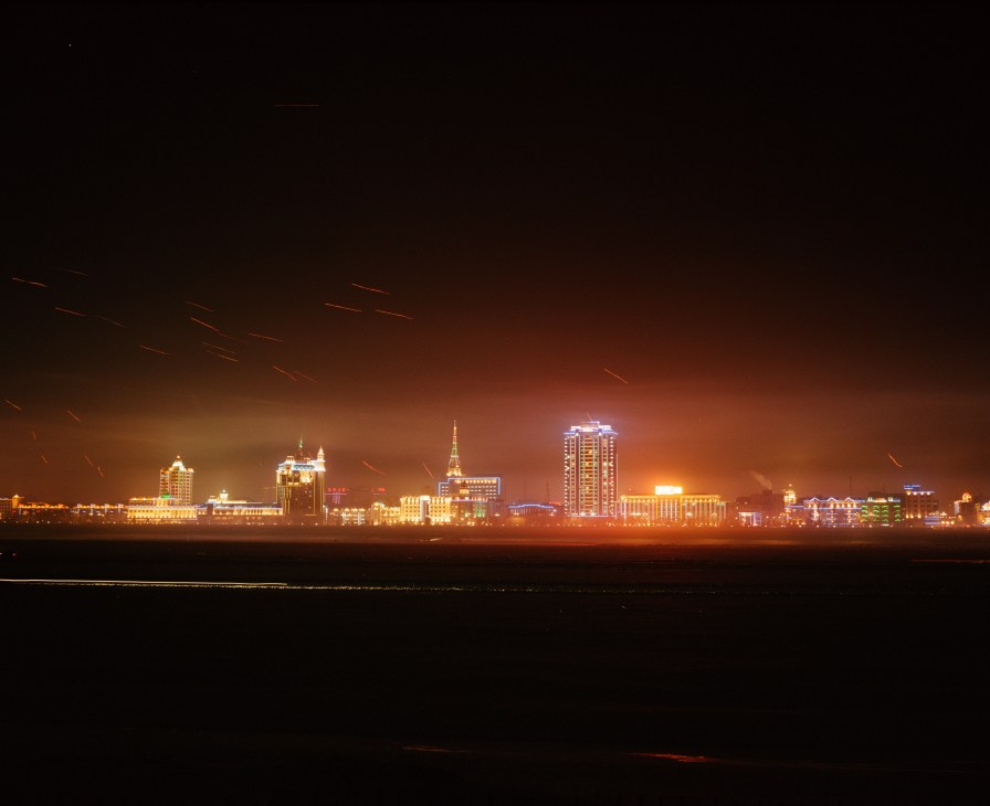 Illuminated skyline of Heihe at night viewed across the frozen Amur River from Russia.