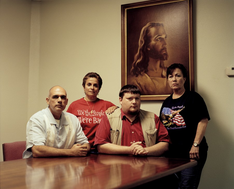 Four members of the McAllen Tea Party sit at a table beneath a portrait of Jesus Christ.
