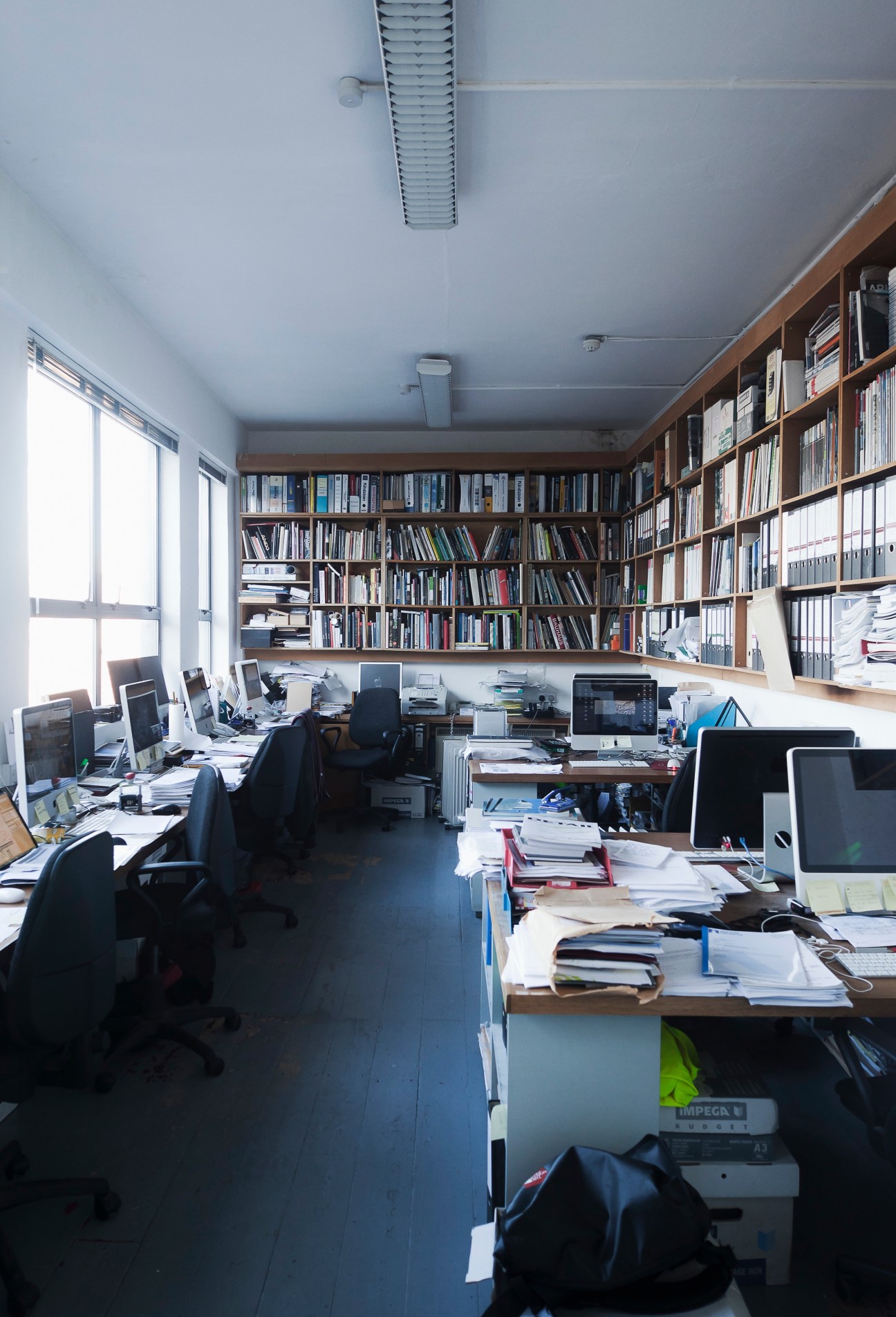 Interior of Grafton Architects office with wooden shelving, computer workstations, and natural light from windows.