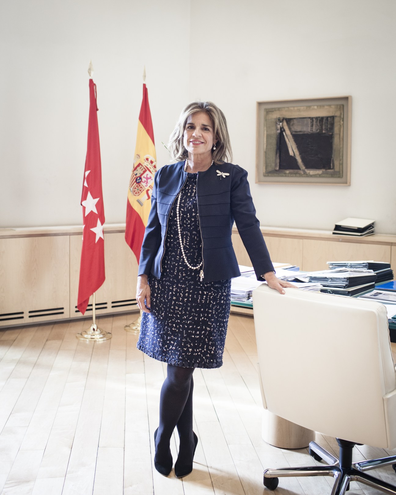 Madrid Mayor Ana Botella standing in her office with Spanish and regional flags behind her.