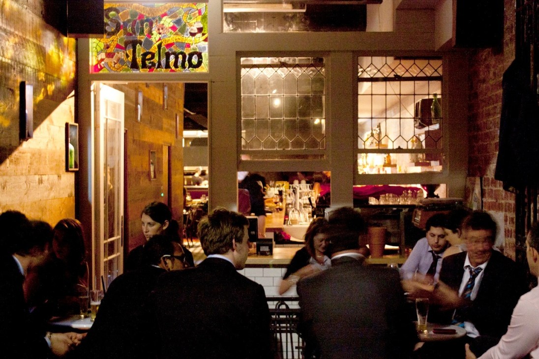 San Telmo restaurant exterior at night with diners visible through windows and colorful neon sign.