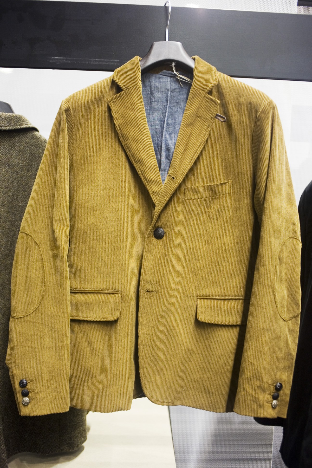 Mustard-yellow corduroy blazer with notch lapels and patch pockets displayed on hanger.