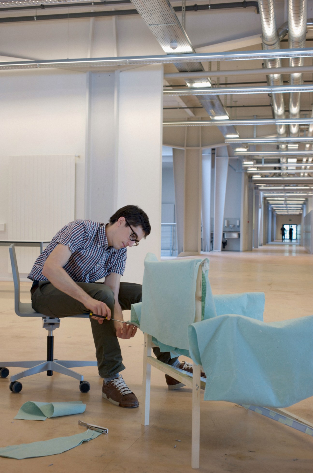 Student Dimitri Baehler works on an upholstered chair prototype in a bright ECAL workshop space.