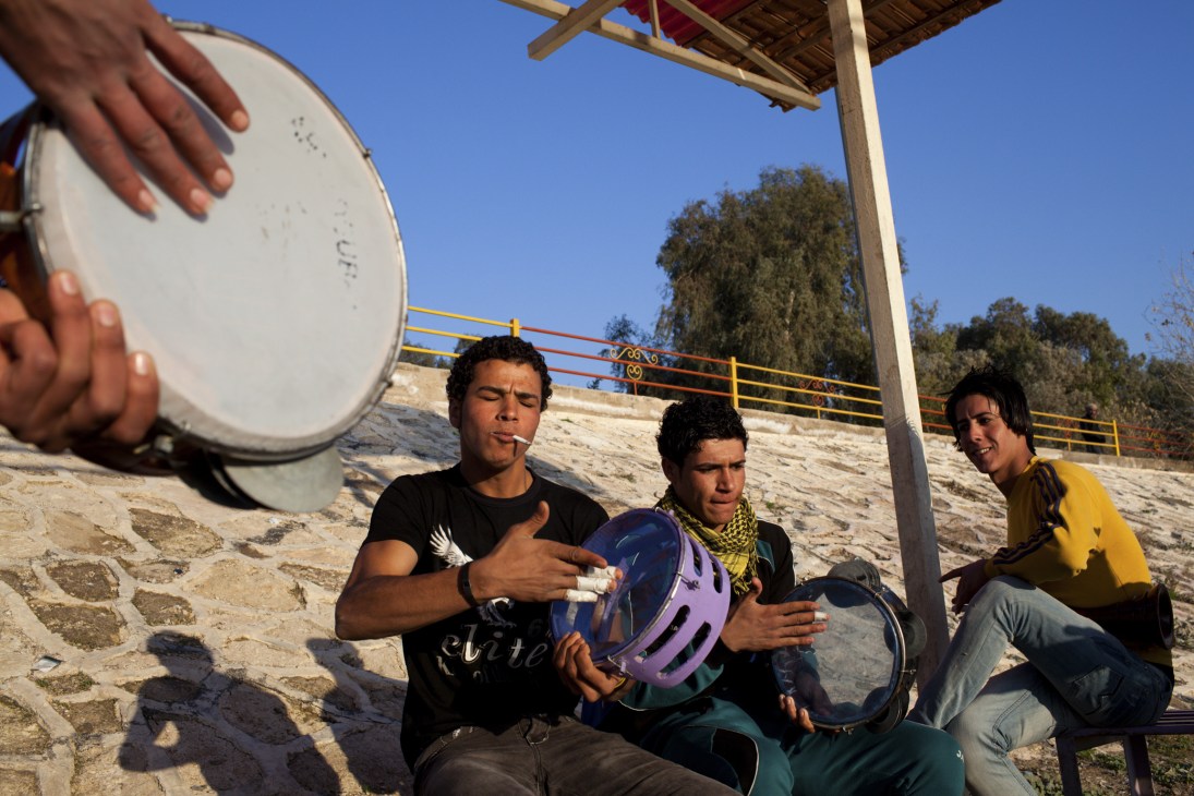 Young musicians playing drums on the banks of the Tigris River in Baghdad.