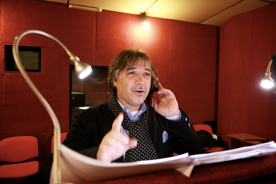 Massimo Rossi, Italian dubbing actor for Sean Penn, wearing headphones in a red recording studio
