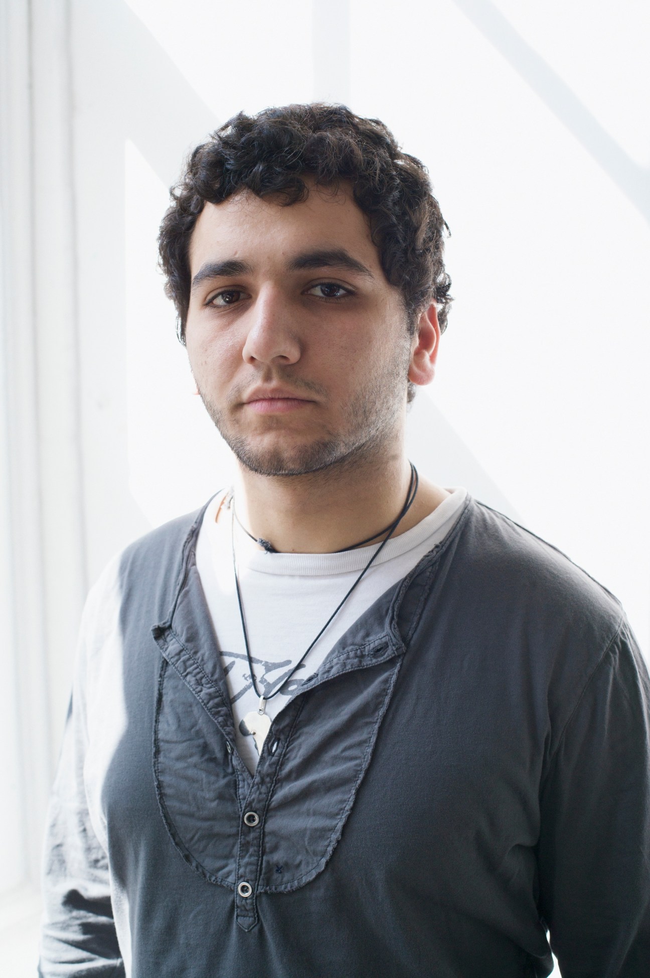 First year student George Massoud poses for a portrait in a white-walled space.