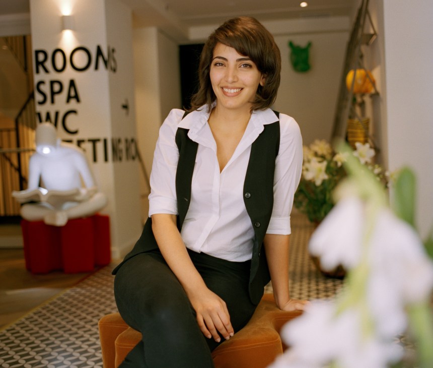 Noa, 26, staff member at the Shenkin hotel, smiling in the hotel lobby.