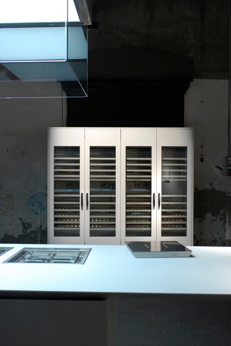 White kitchen storage system with glass-front cabinets displaying shelving, designed by Piero Lissoni for Boffi.