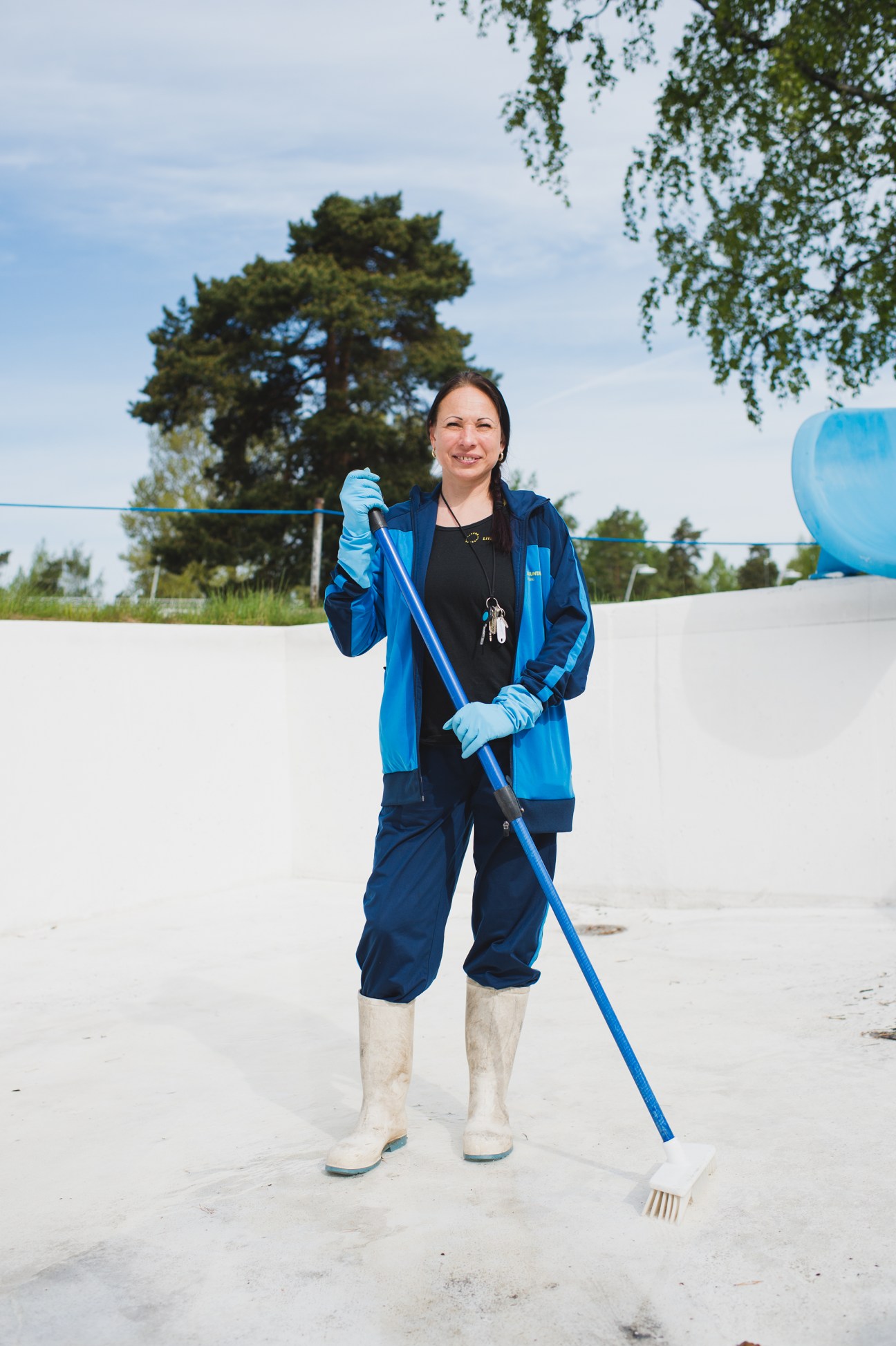 Maarit Töntsi, a stadium employee, holds a cleaning tool while smiling at the Helsinki Swimming Stadium.