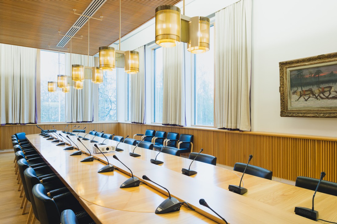 Conference room at Rovaniemi city hall with cylindrical pendant lights, wooden paneling, and expansive windows overlooking winter landscape.