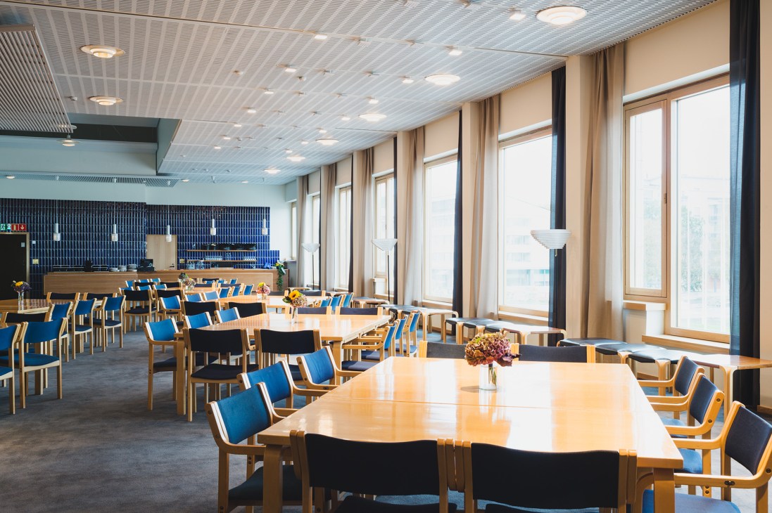 Modern cafeteria with wooden tables, blue and black chairs, and large windows at Lappia Hall.