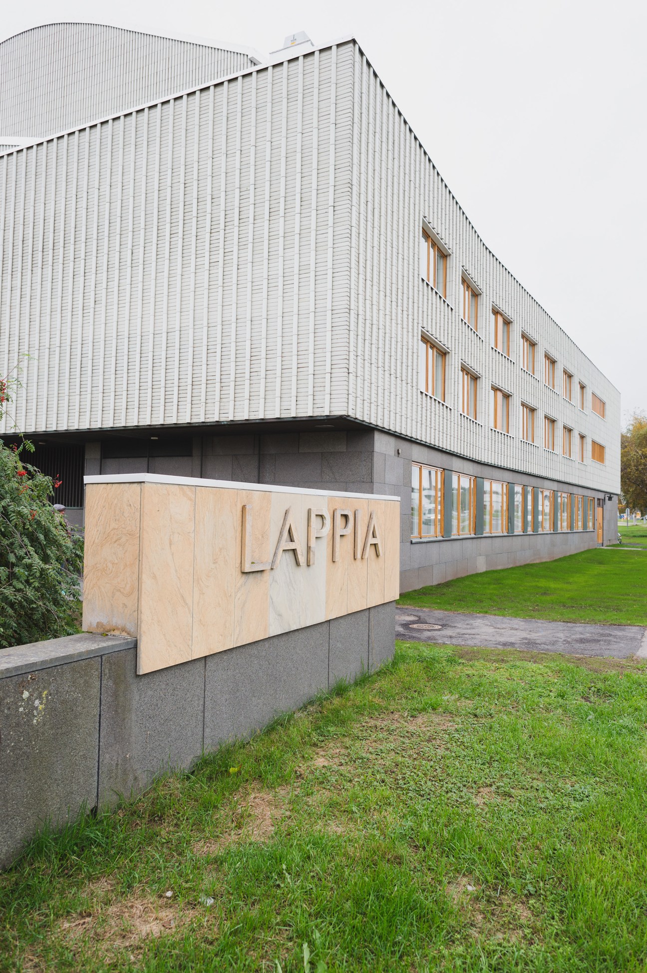 Modern white corrugated metal building with wooden-framed windows and a sign reading LAPPIA on its facade.