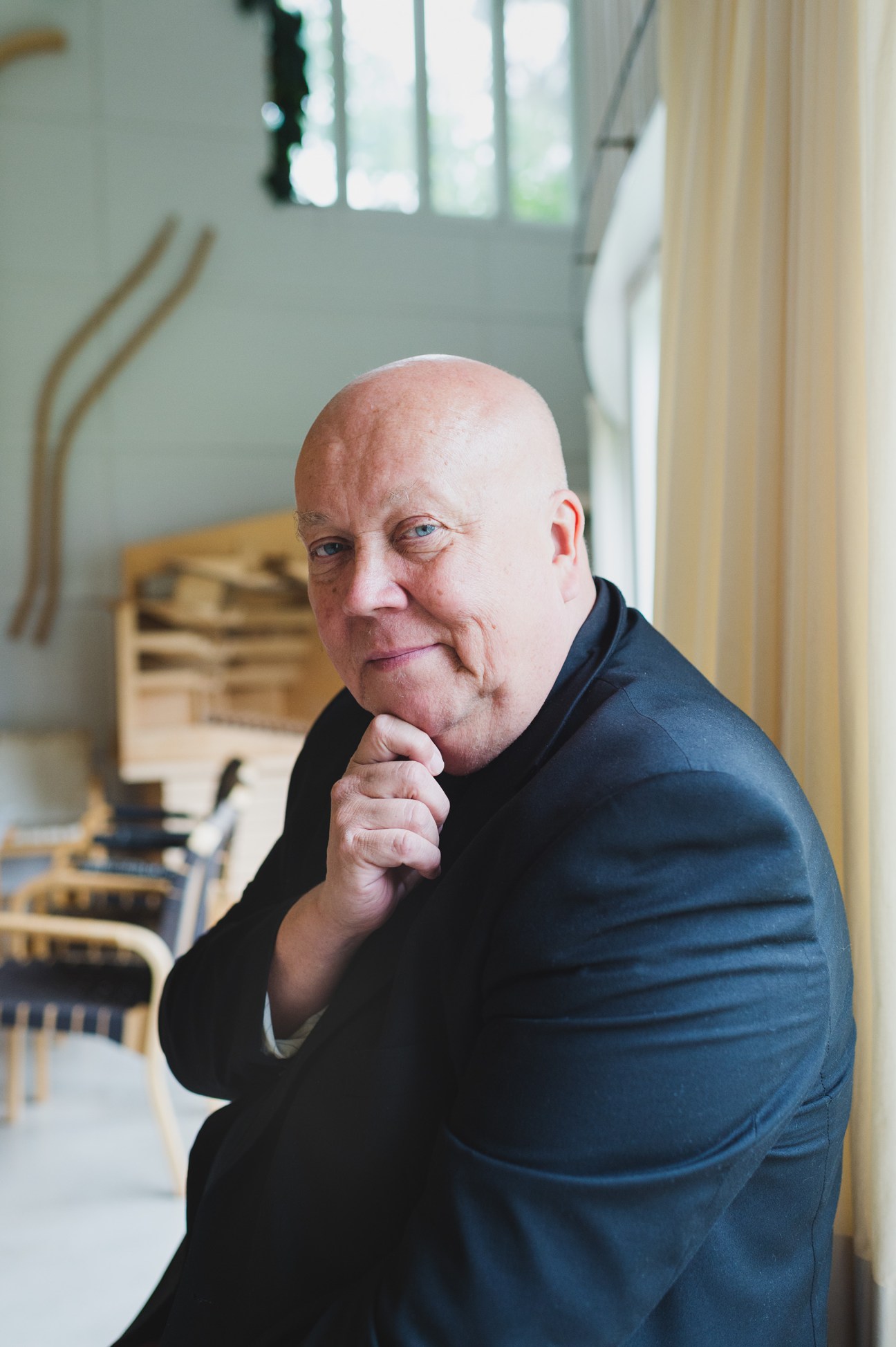 Portrait of Esa Laaksonen, director of Alvar Aalto Academy, in a modern interior with wooden furniture.