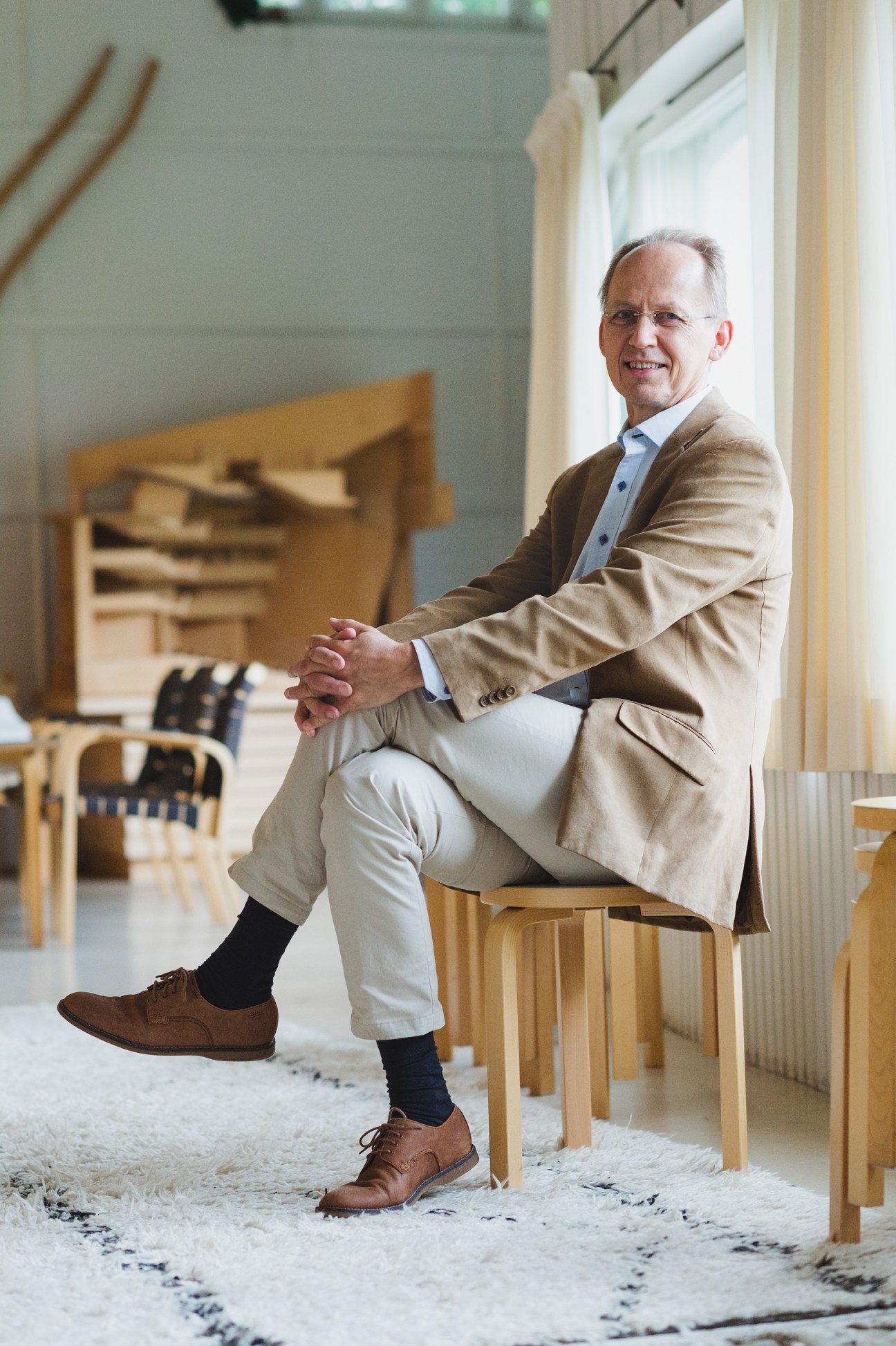 Johannes von Martens of A-Konsultit sits on a wooden chair in a modernist interior space with wooden furniture.