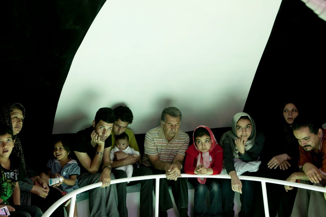 Family of multiple generations looking down through glass-bottomed boat windows at sea life below.