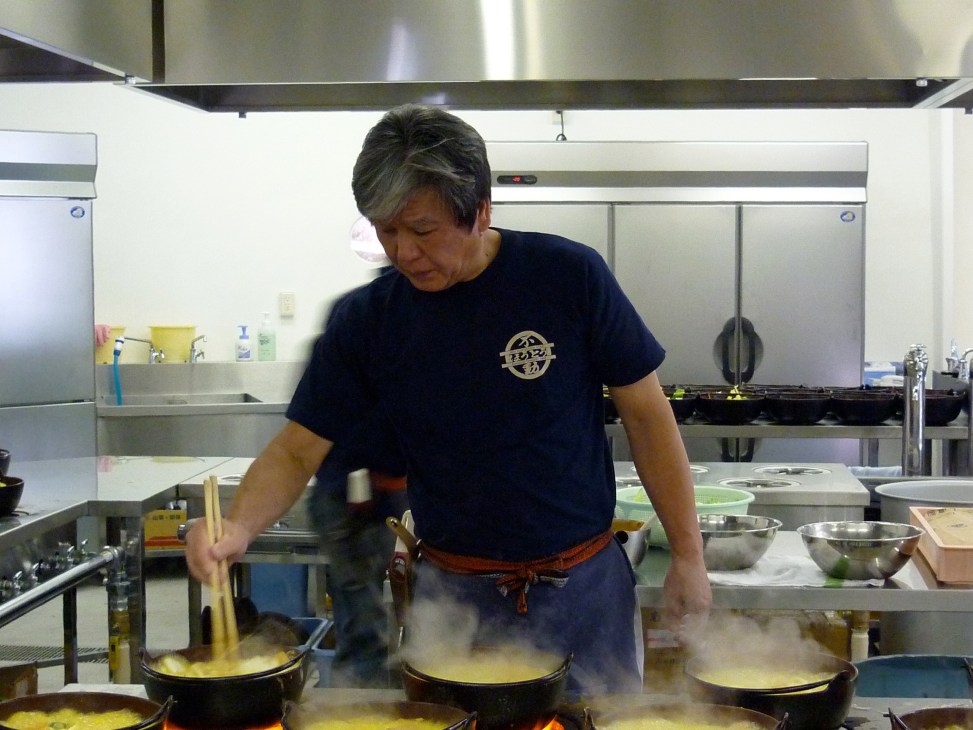 Chef preparing hoto noodles in steaming pots at Hoto Fudo restaurant kitchen.