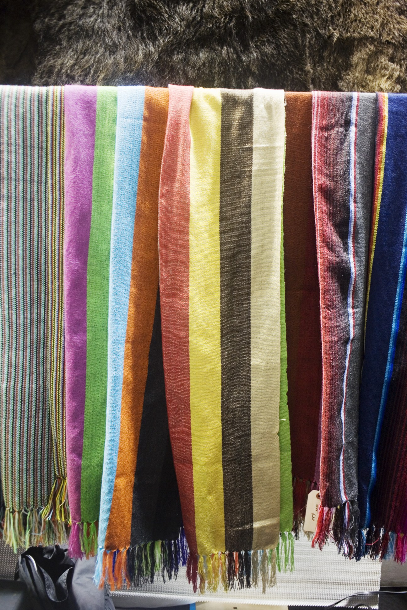 Colorful handwoven scarves with fringe displayed at the Monitaly stand.