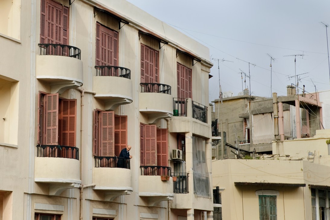 Cream-colored French Mandate-era building with red wooden shutters and curved balconies in Mar Mikhael, Beirut.
