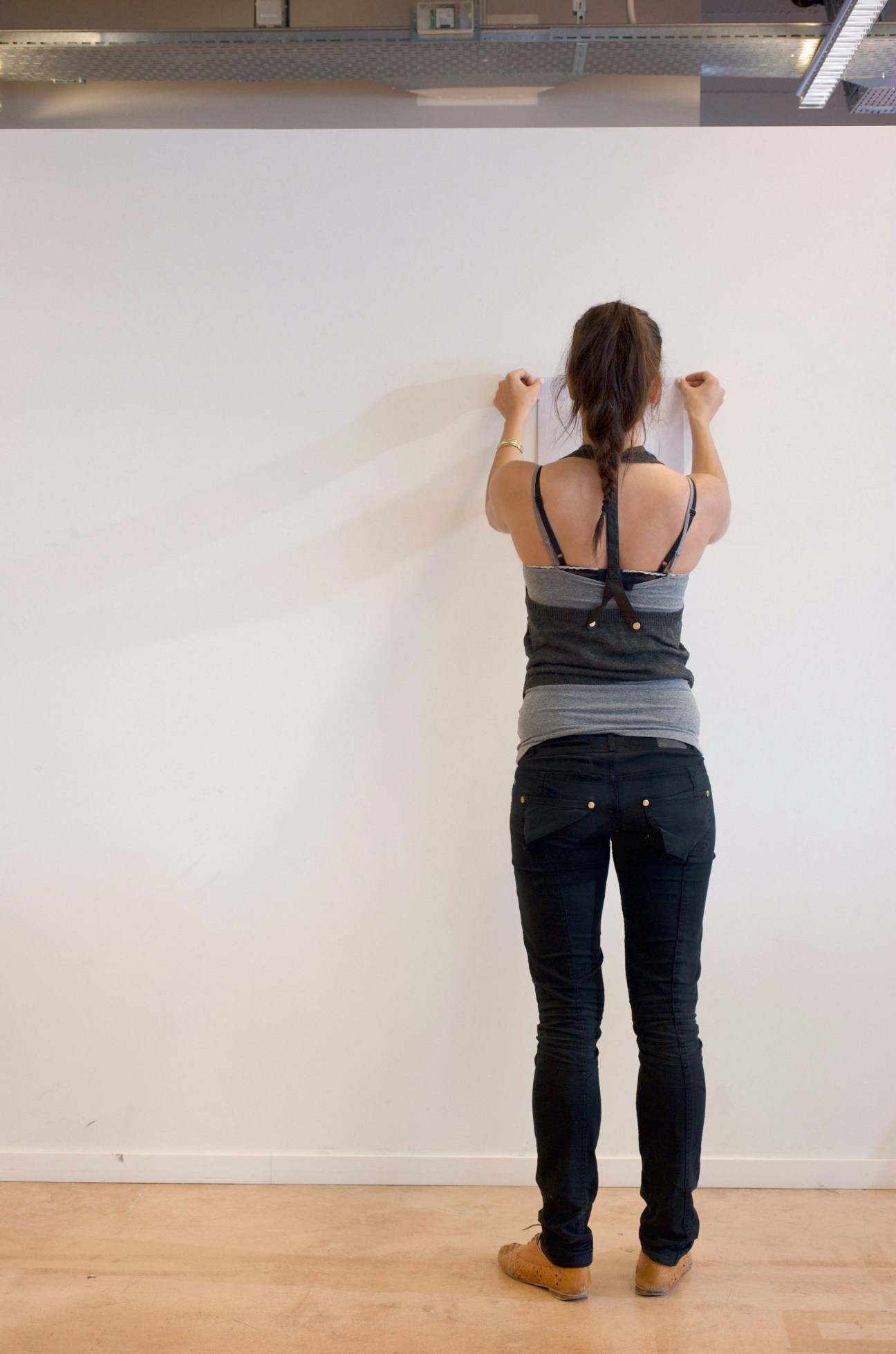 A first-year student hangs her work on a white wall in an ECAL studio space.