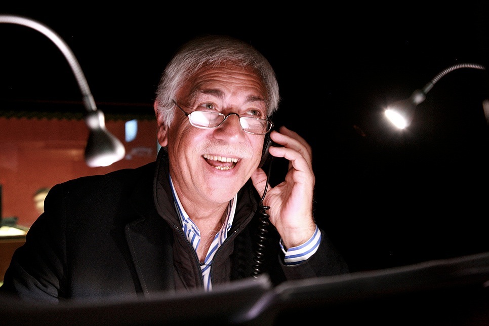 Luigi La Monica, an Italian voice actor, smiling while wearing headphones in a dubbing studio.