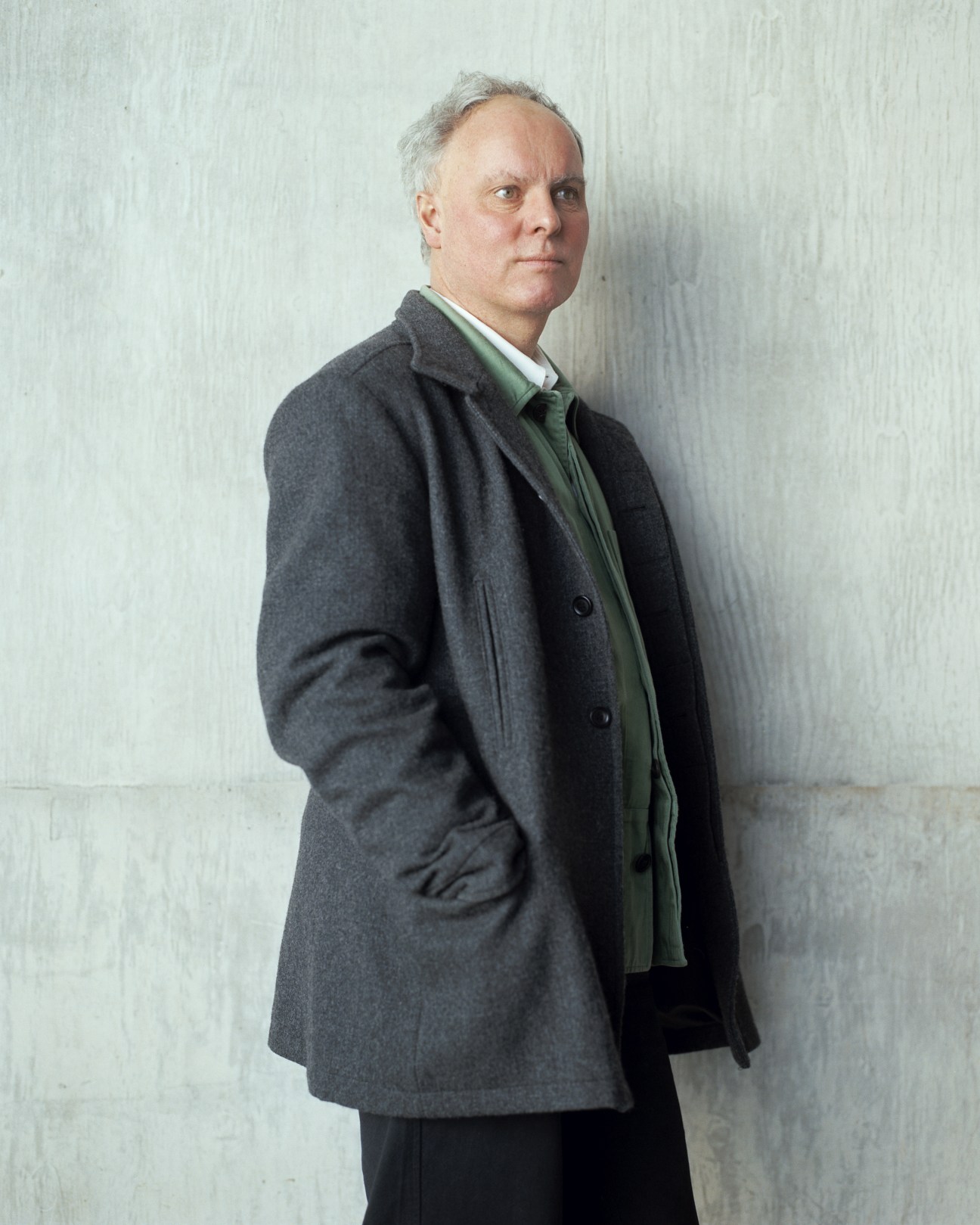 Professor Jeremy Till, head of Central Saint Martins, wearing a grey coat and green scarf against a white wall.