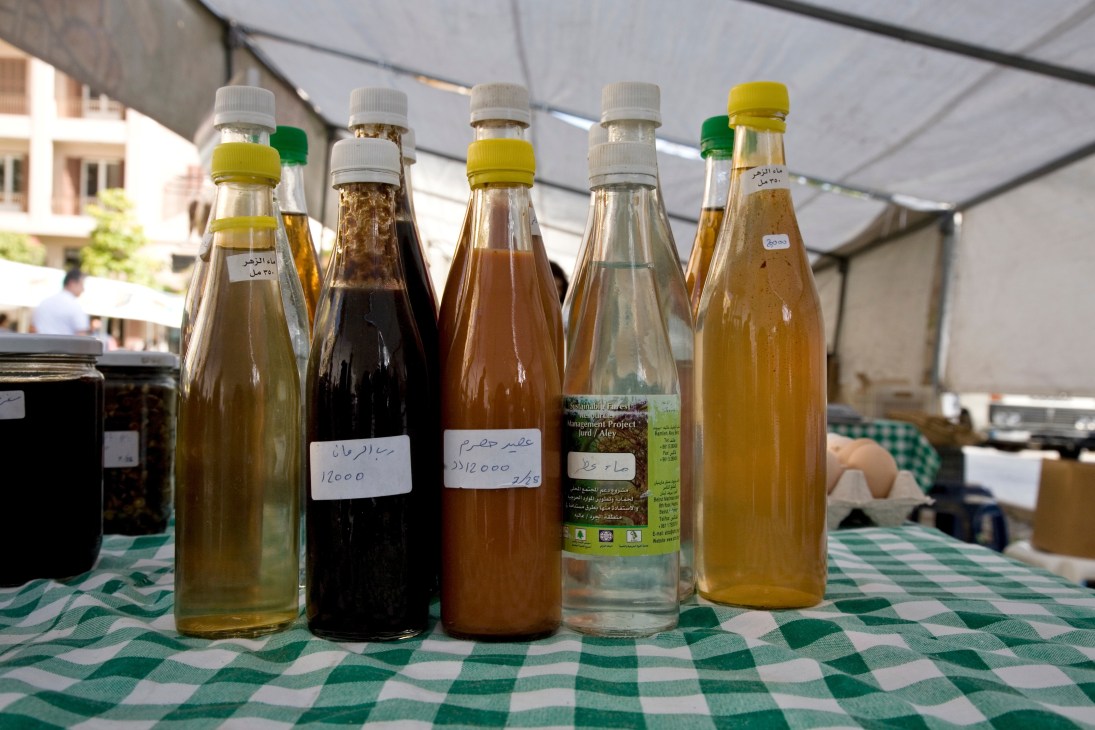 Bottles of homemade flower extract, pomegranate and grape syrups with handwritten labels displayed at Souk el Tayeb market.