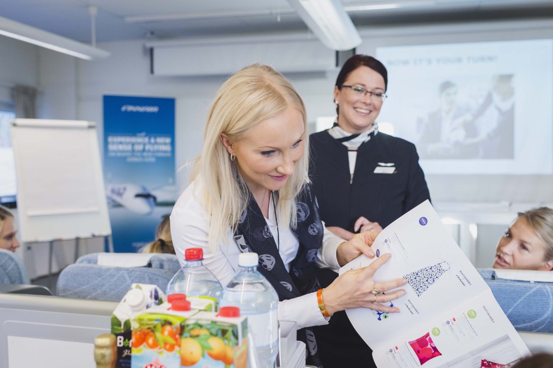 Flight attendant instructor demonstrates communication techniques to students in a classroom at Finnair Flight Academy.