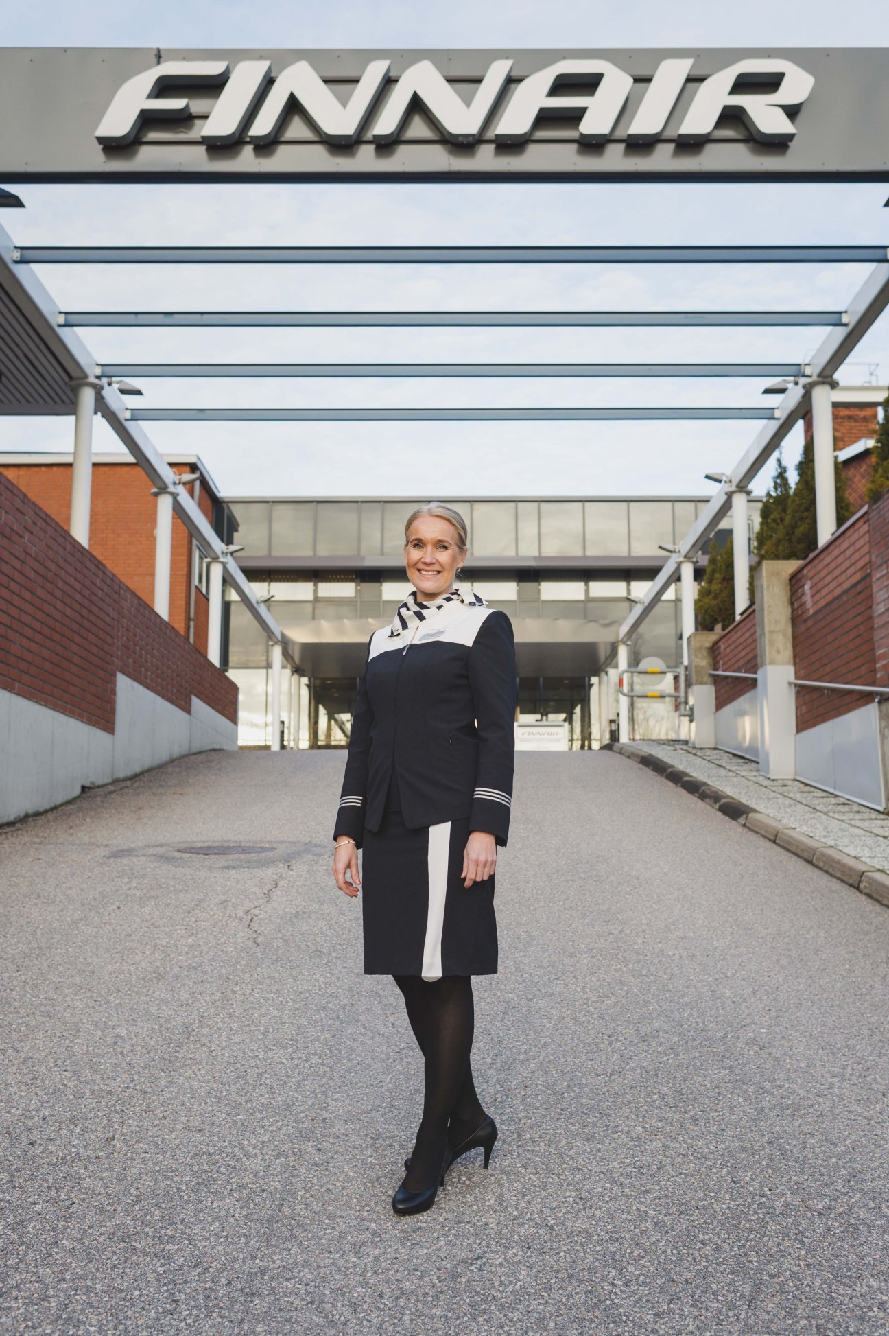Finnair training manager Katja Parviainen in uniform standing outside the Finnair Flight Academy building.