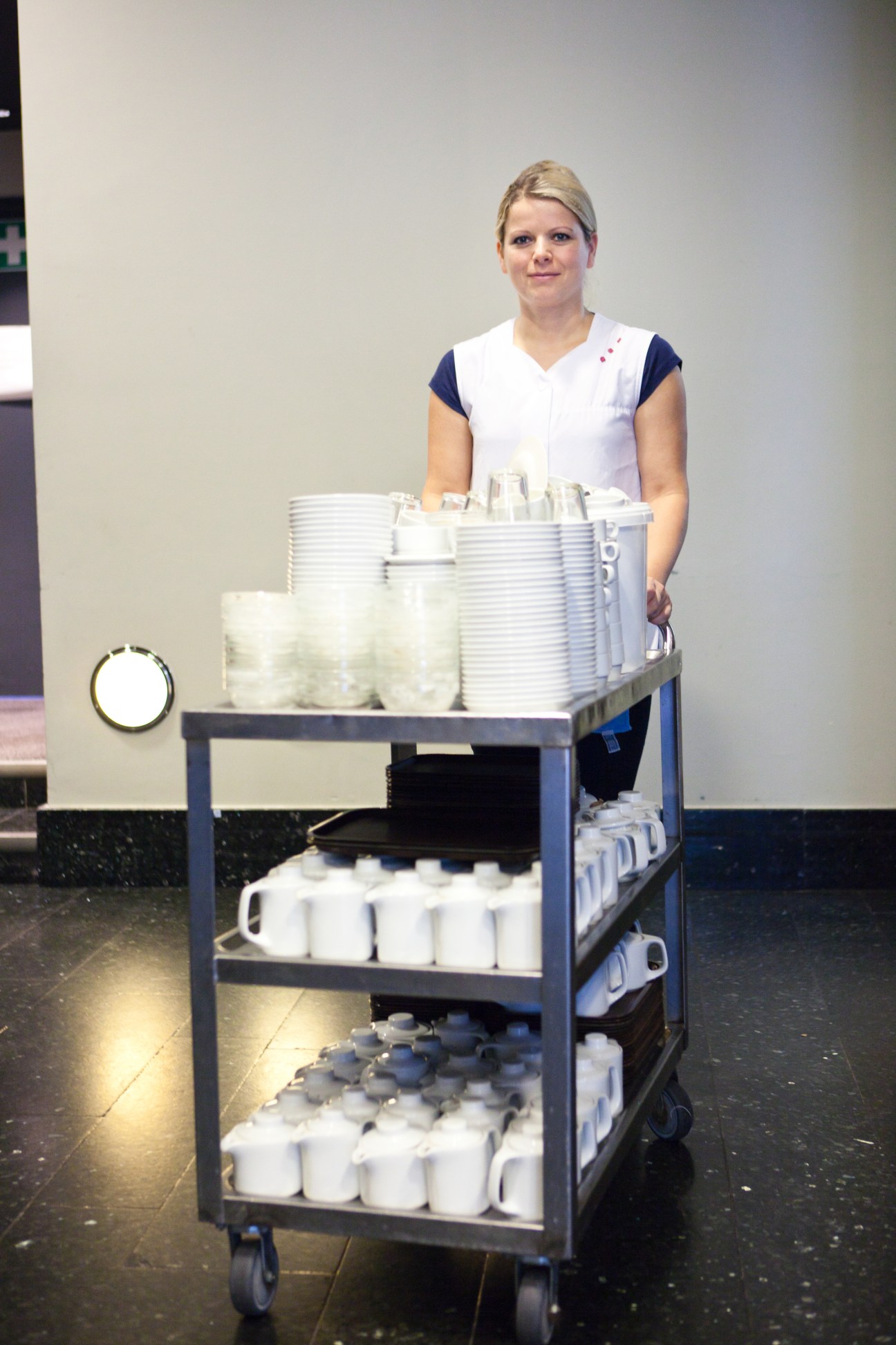 Woman serving coffee from a multi-tiered trolley stacked with white cups and containers at Der Spiegel office.
