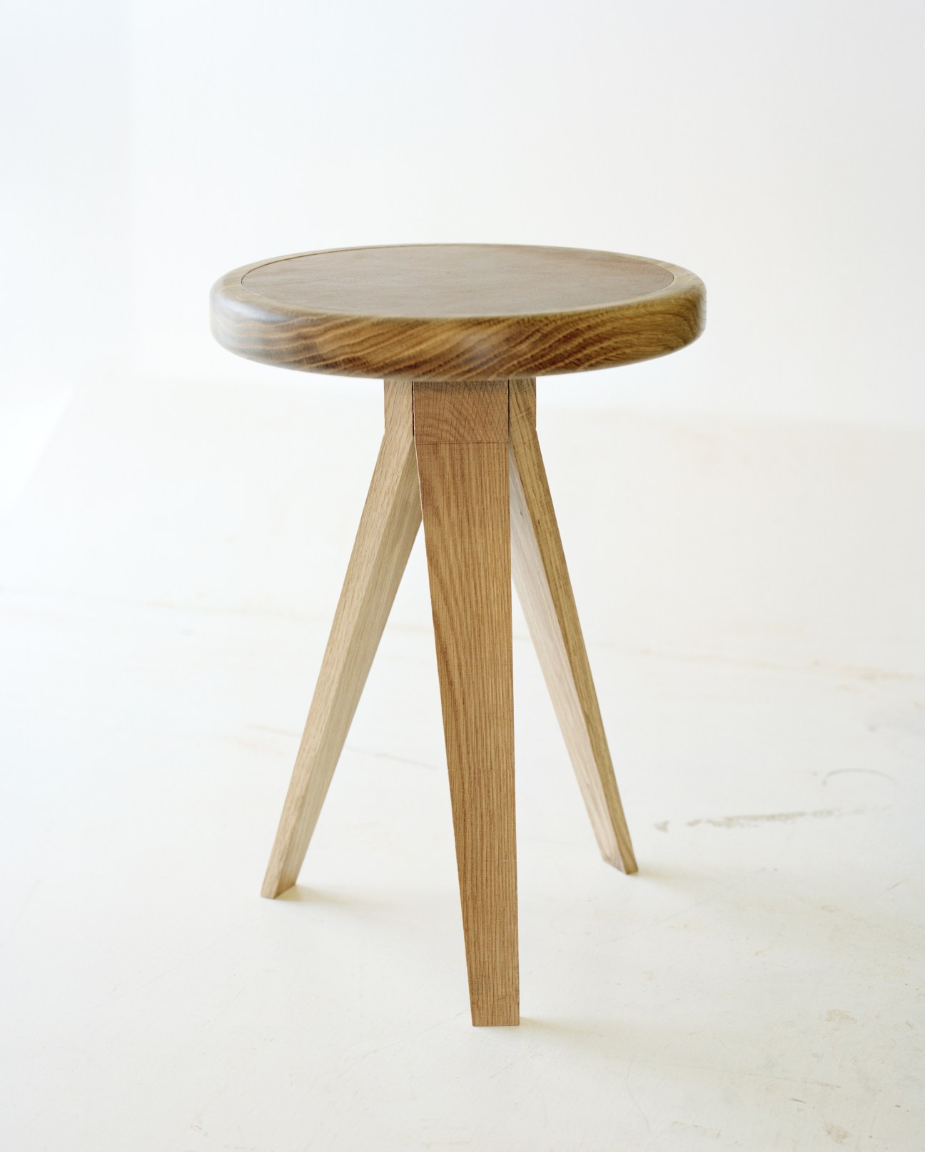 Hand-crafted wooden side table with round top and three angled legs by Young and Norgate.