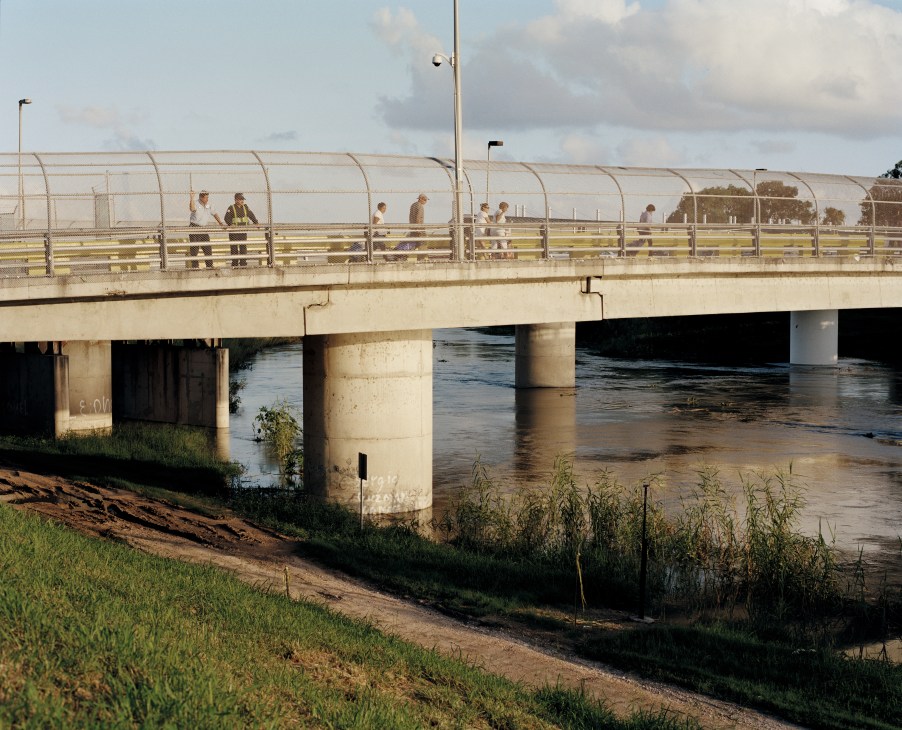 People walking across an official border-crossing bridge over the Rio Grande river in Texas.